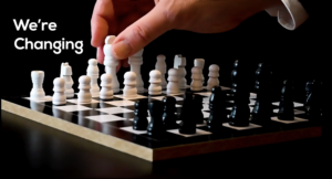 A hand moves a white chess piece on a chessboard with black and white pieces, symbolizing strategic marketing. The text We’re Changing appears on the left side of the image.